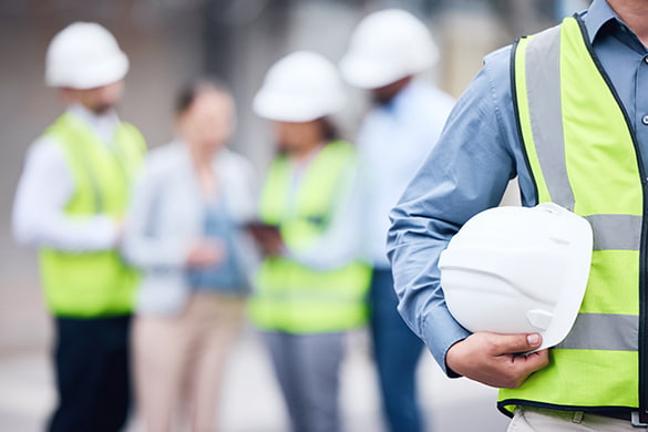 A construction worker hold their hardhat on a construction site