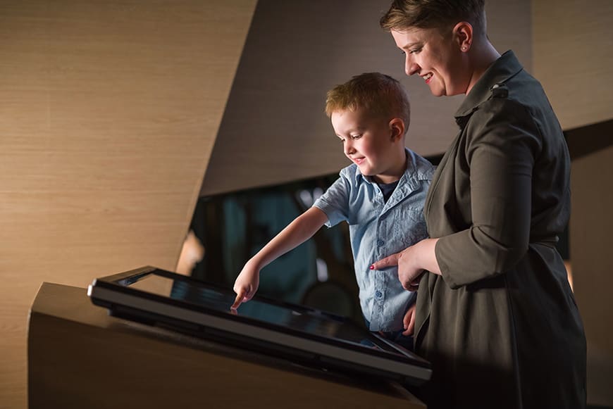 Student and chaperone use a touchscreen at a museum