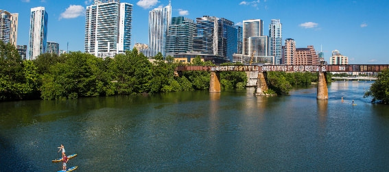 people kayaking at lady bird lake with the city skyline in the background