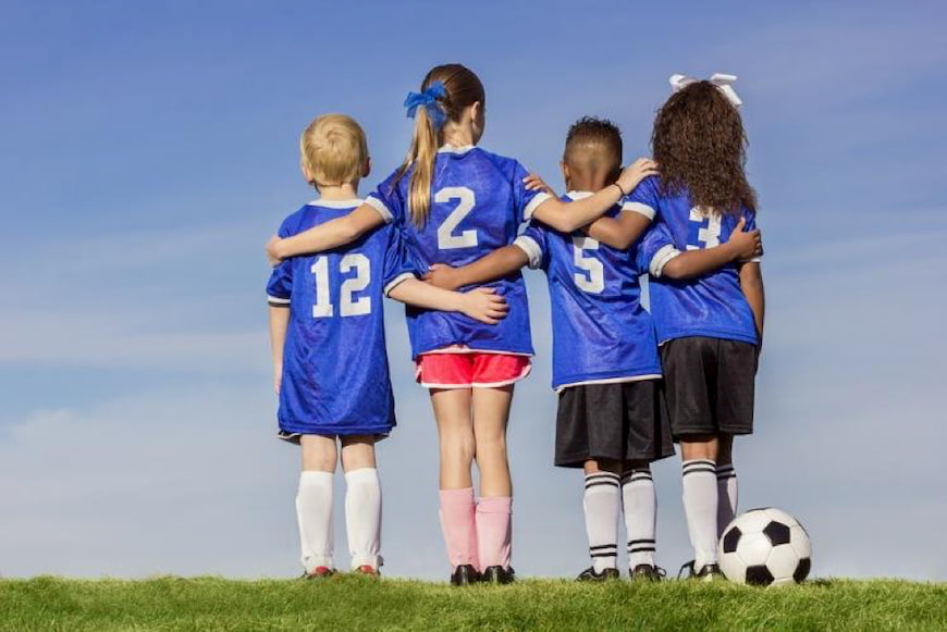 kids stand with their arms around each other after a soccer game